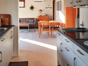 Una cocina moderna con comedor, armarios de madera y un sofá gris.