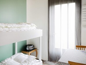 A bunk bed with a radio on a small table beside it, a chair, and a window with sheer curtains. - 6 Person Holiday Home in Hojby (Hojby)