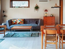 Una sala de estar con sofá, mesa de centro y comedor con sillas.