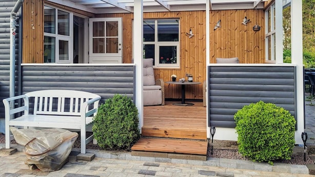 A wooden cabin with a covered porch, a bench, and a small table with chairs. - 7 Person Holiday Home in Hojslev (Hojslev)