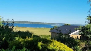 A house with a view of a lake and distant hills. - 7 Person Holiday Home in Hojslev (Hojslev)