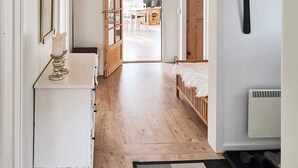 A hallway with a wooden floor, a white dresser, a mirror, and a bed with a white fluffy cover. - 7 Person Holiday Home in Hojslev (Hojslev)