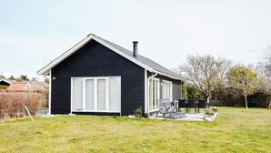 A single-story house with a dark exterior, a large white-framed window, and a chimney. - Tranquil Retreat by the Sea - By Traum Ferienwohnungen (Slagelse)