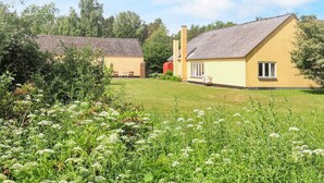 Il s’agit d’une propriété rurale comprenant deux bâtiments : l’un est doté d’un toit en tuiles, l’autre d’un toit à pente, et l’ensemble est entouré d’une végétation luxuriante et d’une pelouse bien entretenue.