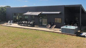 A modern building with a patio area featuring outdoor seating and a hot tub. - 10 Person Holiday Home in Vaeggerlose (Vaeggerlose)