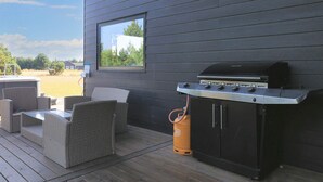 An outdoor patio with wicker furniture, a gas grill, and a window overlooking a grassy area. - 10 Person Holiday Home in Vaeggerlose (Vaeggerlose)