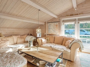 Een gezellig houten interieur met een bank, een bijzettafeltje en een kaart aan de muur.