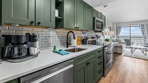 A modern kitchen with green cabinets, a stainless steel sink, and a built-in microwave. - Romantic Oceanfront Condo w/ Beach Access, King Bed, Onsite Bar & Restaurant! (Myrtle Beach)