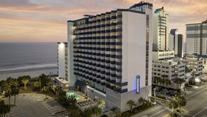 A modern hotel with a pool, located near a beach. - Romantic Oceanfront Condo w/ Beach Access, King Bed, Onsite Bar & Restaurant! (Myrtle Beach)