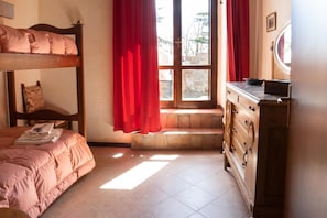 Une chambre avec un lit superposé, une commode et une fenêtre avec des rideaux.