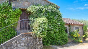 Un edificio de piedra con puerta de madera, una escalera y un pequeño jardín.