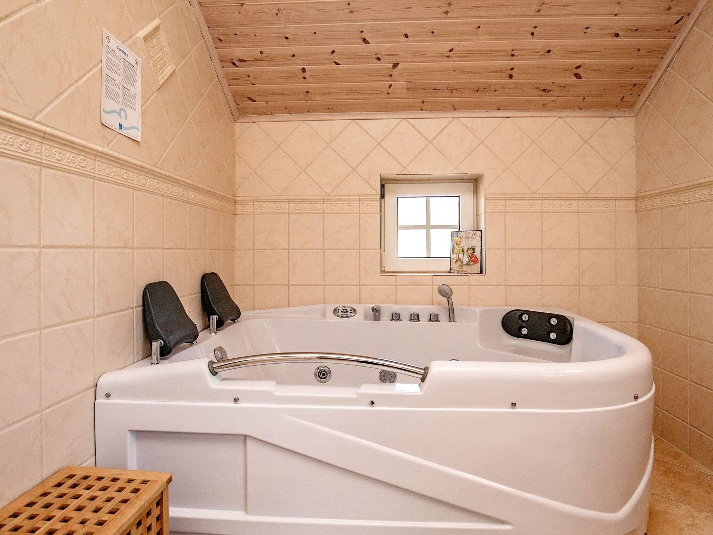 Ein Badezimmer mit einer freistehenden Badewanne, einem Fenster und einem hölzernen Hocker.
