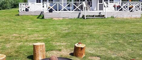 A house with a deck, a fire pit, and a grassy yard.