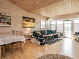 Un salón amplio con techo de madera, una mesa de comedor, un sofá y un ventanal grande.
