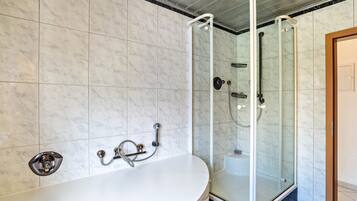 Ein Badezimmer mit einer freistehenden Badewanne, einer Duschkabine aus Glas und einer Wand mit Marmorfliesen.