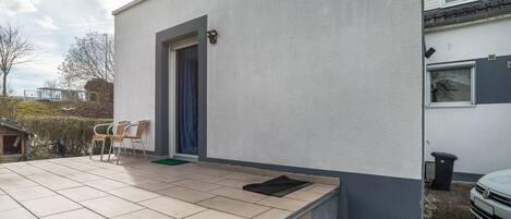Een woongebouw met een betegeld terras, een deur en een schotelantenne.