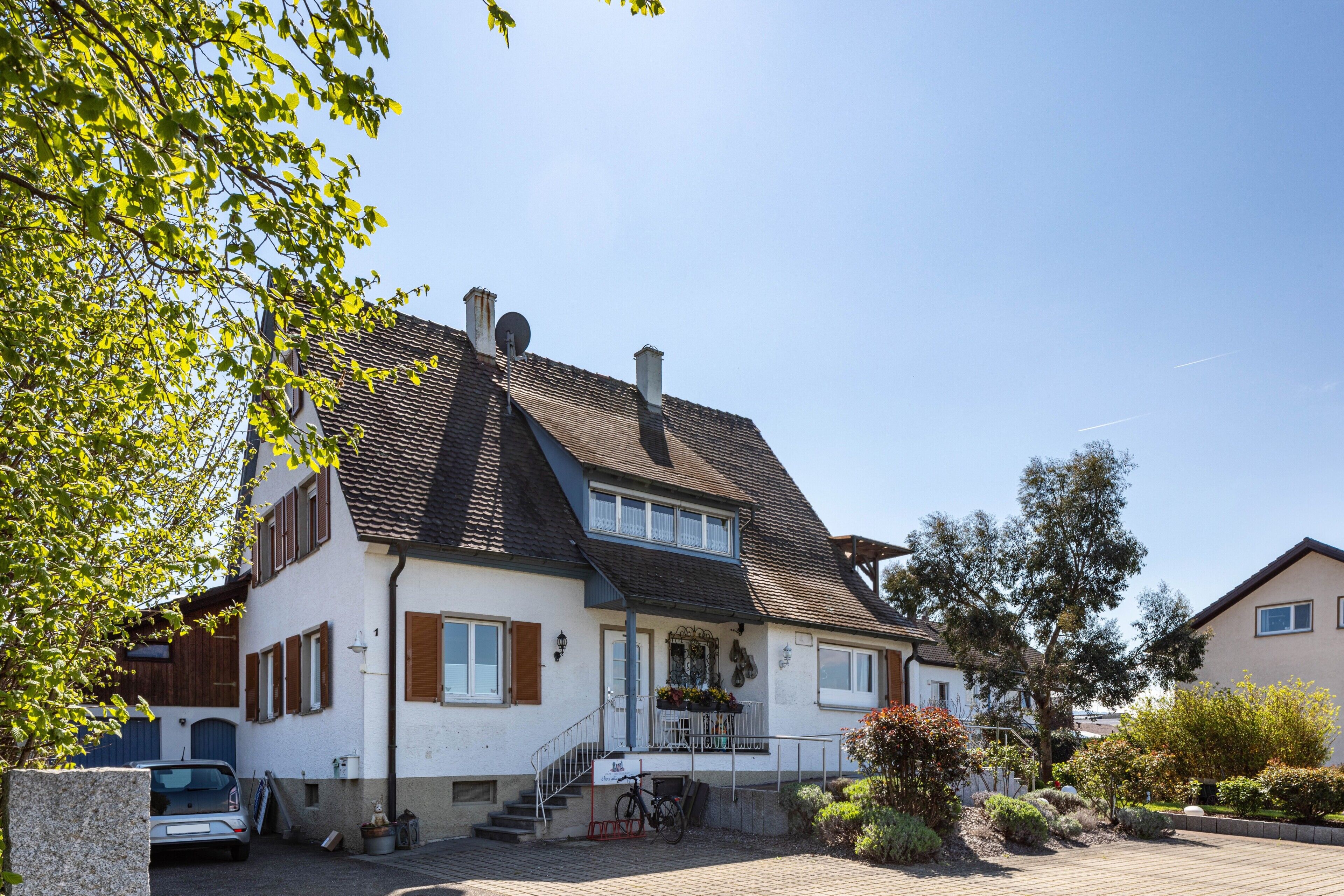 Une maison à deux étages avec un porche à l’avant, un escalier et une allée.