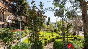A garden with a pathway, a wooden fence, and a building with a balcony.