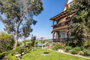 A two-story building with a balcony, surrounded by a well-maintained garden with various plants and flowers. - Apartment 'Ferienwohnung Trixi' with Shared Garden, Balcony and Wi-Fi (Sexau)