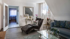A modern living room with a sofa, a recliner, a glass coffee table, and a side table with decorative items.