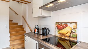Une cuisine avec un escalier en bois, une cuisinière encastrée et une hotte aspirante fixée au mur.