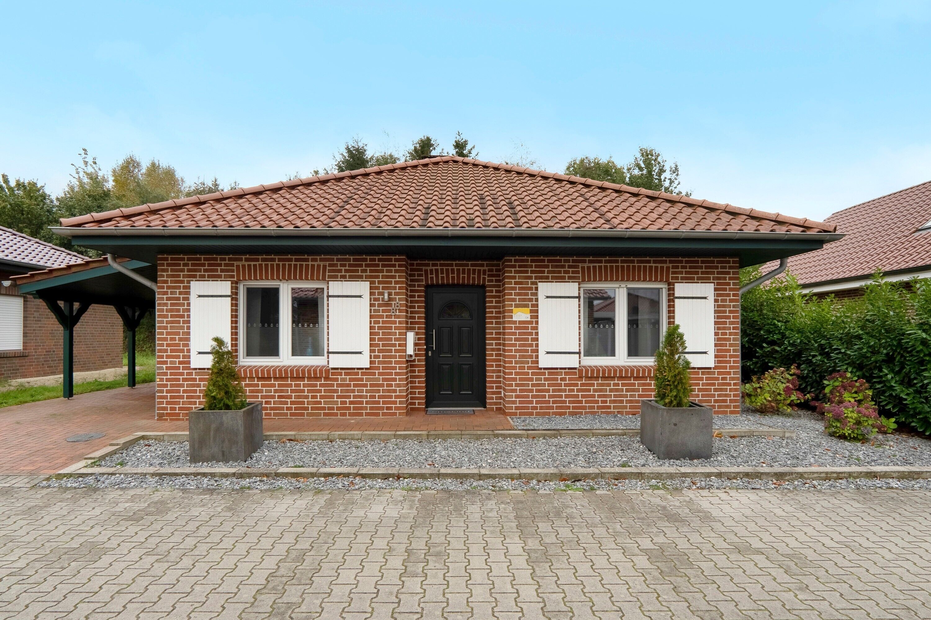 Ein zweigeschossiges Backsteinhhaus mit Ziegeldach, einer schwarzen Haustür und zwei Fensterläden.