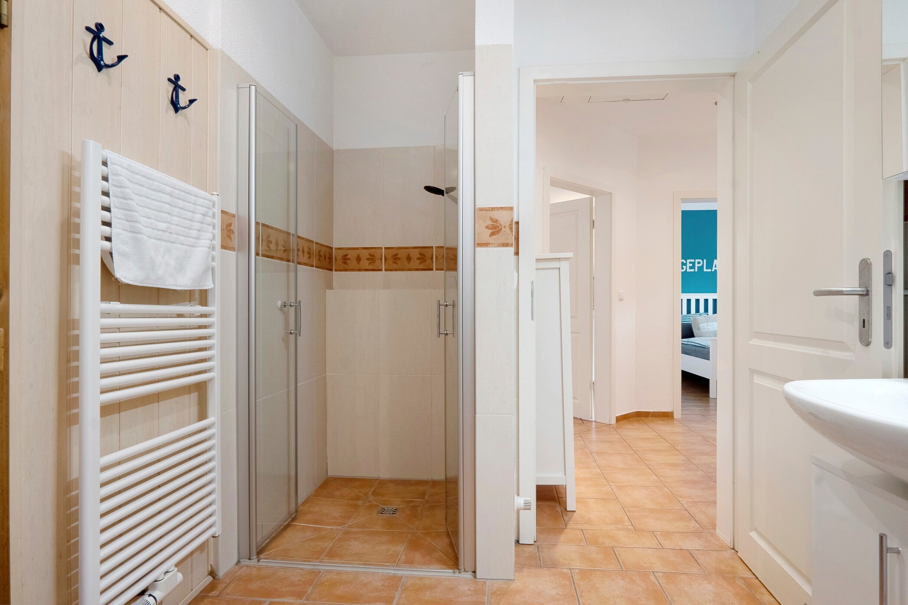 A hotel bathroom with a shower, a towel rack, and a sink.