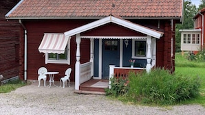 A red wooden house with a tiled roof, a porch with white railings, and two white chairs outside. - 4 Person Holiday Home in Tallberg-by Traum (Tallberg)