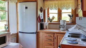 A compact kitchen with wooden cabinets, a white refrigerator, a stove, and a window with lace curtains. - 4 Person Holiday Home in Tallberg-by Traum (Tallberg)
