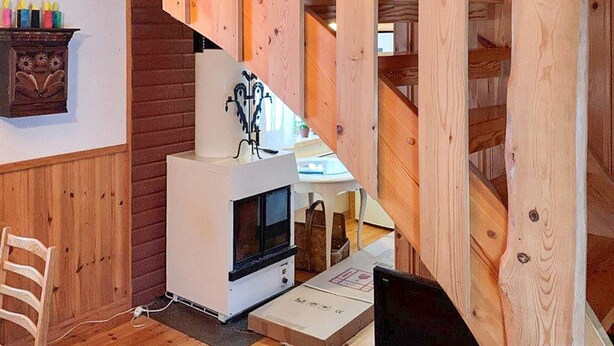 A wooden interior with a white fireplace, a wooden staircase, and a small table with candles. - 4 Person Holiday Home in Tallberg-by Traum (Tallberg)