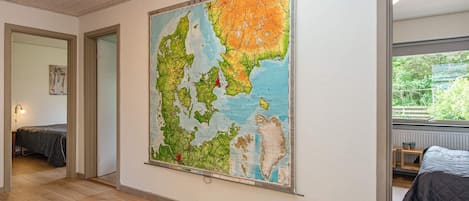 A room with a large map on the wall, wooden flooring, and a bed with a grey duvet.