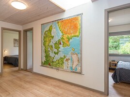 A room with a large map on the wall, wooden flooring, and a bed with a grey duvet.