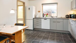 A compact kitchen with a refrigerator, a coffee maker, and a window with a view. - 8 Person Holiday Home in Struer (Struer)