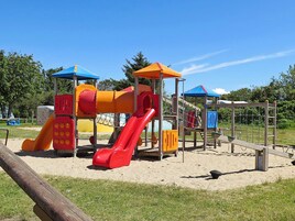 A playground with a slide, climbing net, and various play structures.