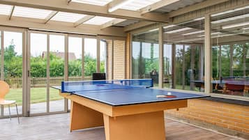 Ein Tischtennis-Tisch in einem überdachten Außenbereich mit Glaswand.