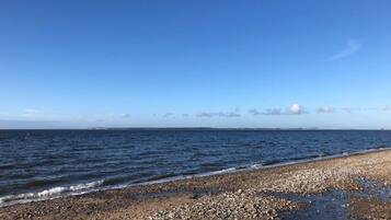Ein Strand mit Kieselsteinen und blauem Himmel.
