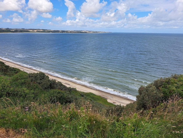 A coastal landscape with a beach, ocean, and distant land.