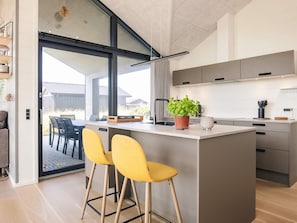 Una cocina moderna con una isla central, taburetes de bar y una planta en maceta.