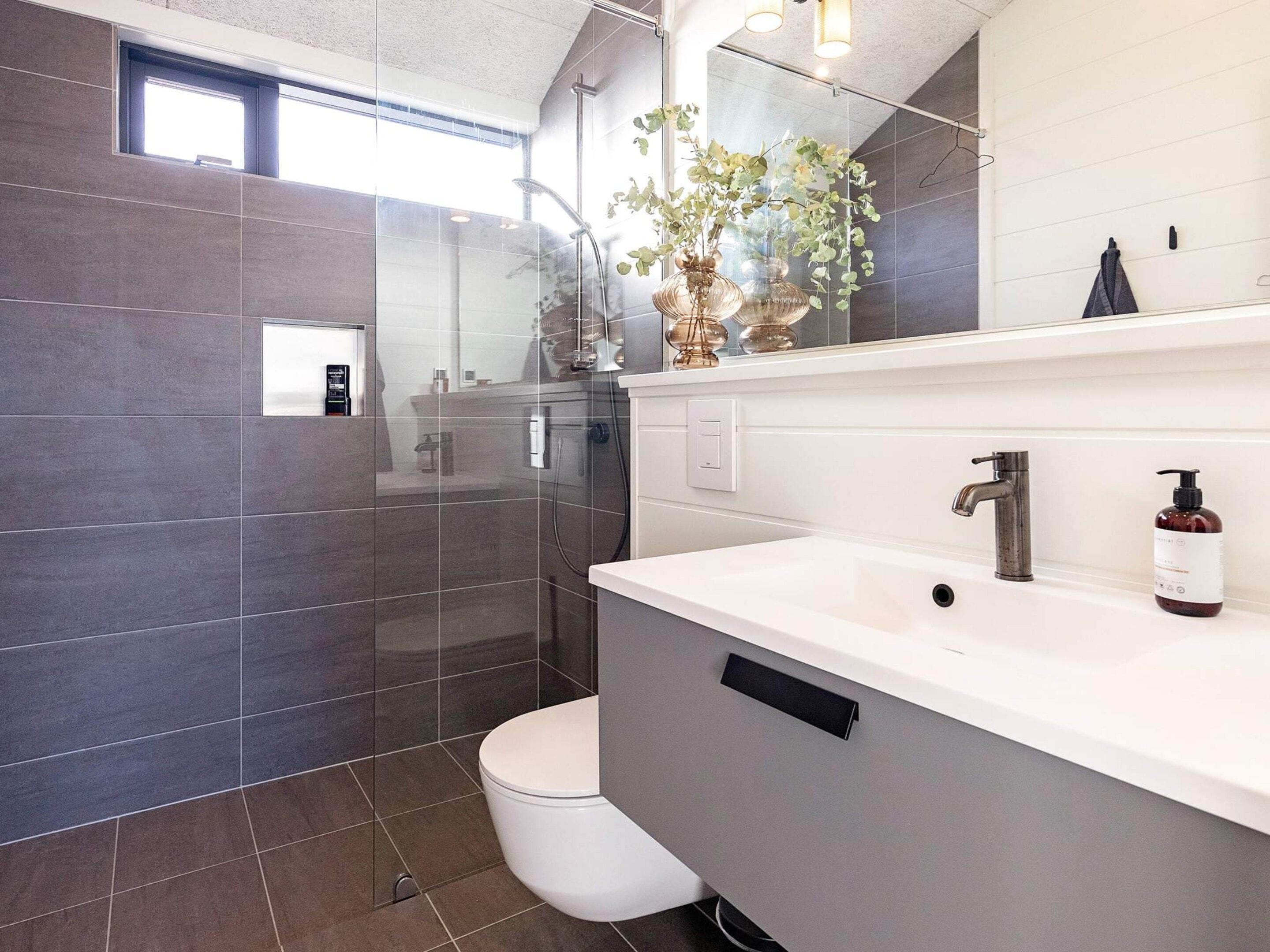 Une salle de bain moderne avec une douche à parois de verre, un lavabo blanc et un grand miroir.