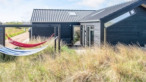 A modern house with a dark exterior, a sloped roof, and a large window. - 8 Person Holiday Home in Hirtshals (Hirtshals)
