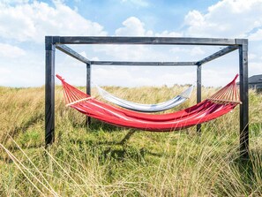 A hammock suspended between two wooden posts in a grassy field. - 8 Person Holiday Home in Hirtshals (Hirtshals)