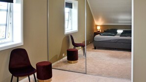 A bedroom with a bed, a chair, a small stool, and a nightstand with a lamp. - 8 Person Holiday Home in Frei (Kristiansund)