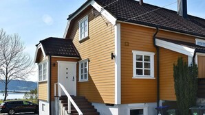 A two-story house with a brown exterior, white trim, and a visible staircase leading to the entrance. - 8 Person Holiday Home in Frei (Kristiansund)