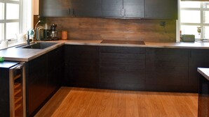 A modern kitchen with dark cabinets, a wooden countertop, and a built-in sink. - 8 Person Holiday Home in Frei (Kristiansund)