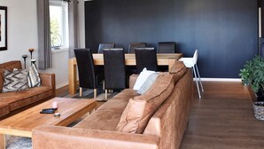 A modern living room with a sofa, coffee table, and dining area with chairs. - 8 Person Holiday Home in Frei (Kristiansund)