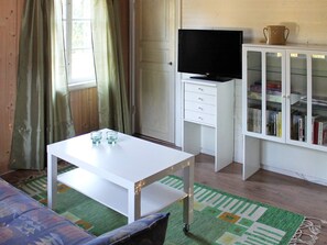 A room with a white desk, a television on a cabinet, and a bookshelf filled with books. - 6 Person Holiday Home in Stjarnhov (Stjarnhov)