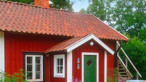 A red wooden house with a green door, white windows, and a red tiled roof. - 6 Person Holiday Home in Stjarnhov (Stjarnhov)