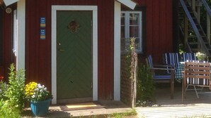 A red building with a green door, a small window, and a porch with chairs. - 6 Person Holiday Home in Stjarnhov (Stjarnhov)