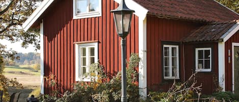 Ein rotes Holzhaus mit weißem Zierfach, Schornstein und Fenster.