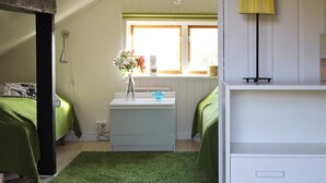 A bedroom with two beds, a small desk with a vase of flowers, a lamp, and a window with a view. - 6 Person Holiday Home in Stjarnhov (Stjarnhov)
